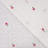 Lähikuvassa kukkakirjonta valkoisella kudotulla puuvillalla.