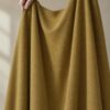 Ochre merino wool jersey, held up in the hand