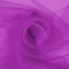 Magenta organza pehmeinä laskoksina, kevyt ja läpikuultava kangas