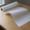 Vlieseline S320 stift strygeindlæg i hvid, rullet ud og buet op i enden, fordi det er for stift til at folde (AI-genereret illustration)